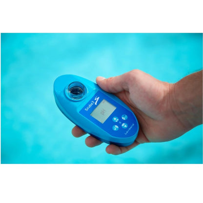 Mano sosteniendo un medidor digital de pH scuba 3 color azul sobre el agua de una piscina, utilizado para analizar la calidad del agua